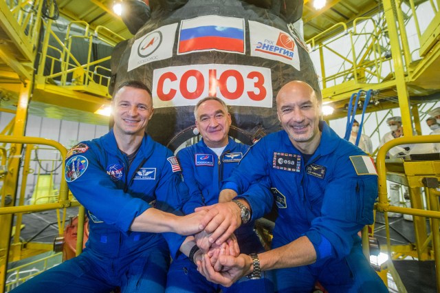 jsc2019e038380 (July 5, 2019) --- At the Baikonur Cosmodrome in Kazakhstan, Expedition 60 crewmembers Drew Morgan of NASA (left), Alexander Skvortsov of Roscosmos (center) and Luca Parmitano of the European Space Agency (right) pose for pictures July 5 in front of their Soyuz spacecraft during pre-launch preparations. They will launch July 20 on the Soyuz MS-13 spacecraft from the Baikonur Cosmodrome for a mission on the International Space Station. Credit: Andrey Shelepin/GCTC