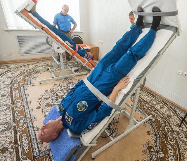 jsc2019e039266 (July 12, 2019) --- At the Cosmonaut Hotel crew quarters in Baikonur, Kazakhstan, Expedition 60 crewmembers Luca Parmitano of the European Space Agency (foreground) and Drew Morgan of NASA test out their vestibular systems on tilt tables July 12 as part of pre-launch activities. Along with Alexander Skvortsov of Roscosmos, they will launch July 20 on the Soyuz MS-13 spacecraft from the Baikonur Cosmodrome in Kazakhstan on a mission to the International Space Station. Credit: Andrey Shelepin/GCTC
