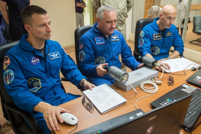 jsc2019e039265 (July 12, 2019) --- At the Cosmonaut Hotel crew quarters in Baikonur, Kazakhstan, Expedition 60 crewmembers Drew Morgan of NASA (left), Alexander Skvortsov of Roscosmos (center) and Luca Parmitano of the European Space Agency (right) practice rendezvous and docking techniques on a laptop computer simulator July 12 as part of pre-launch activities. They will launch July 20 on the Soyuz MS-13 spacecraft from the Baikonur Cosmodrome in Kazakhstan on a mission to the International Space Station. Credit: Andrey Shelepin/GCTC