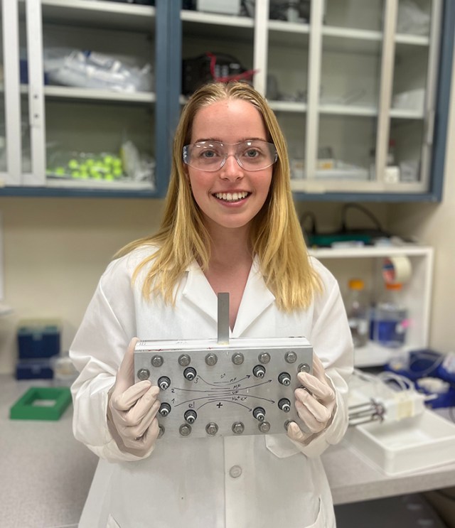 Princeton University undergraduate Kate Sheldon in a lab, holding a rectangular device in both hands