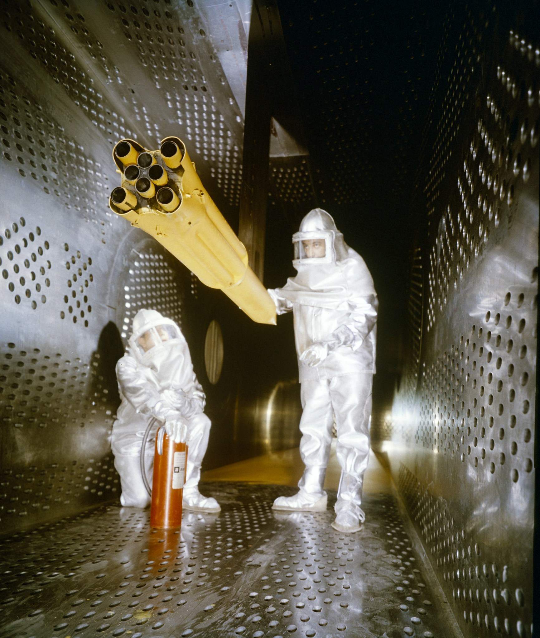 Two men in protective suits with rocket model.