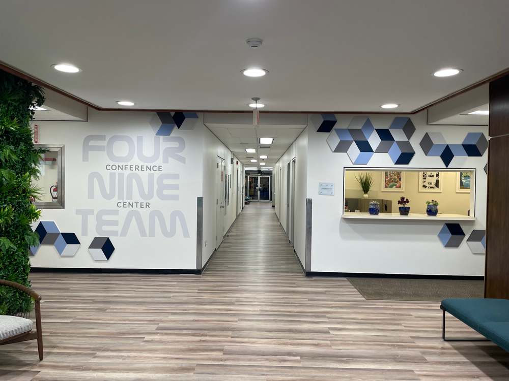 Lobby of a building with brown floors and white walls with colorful art on walls.