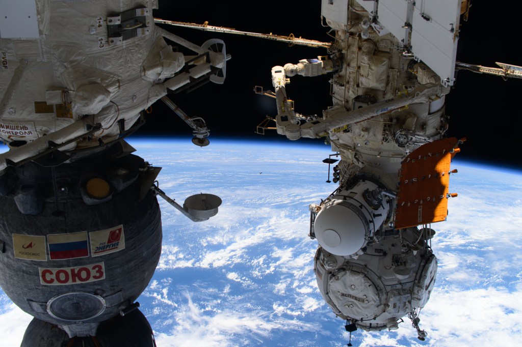 Just a tiny image in the center of this photograph, the Soyuz MS-25 crew ship carrying three crew members is pictured approaching the International Space Station for a docking to the Poisk module. Aboard the Soyuz MS-25 were, NASA astronaut Tracy C. Dyson, Roscosmos cosmonaut Oleg Novitskiy, and Belarus spaceflight participant Marina Vasilevskaya. At left, is the Soyuz MS-24 crew ship docked to the Rassvet module, and at right, is the Prichal docking module attached to the Nauka science module.