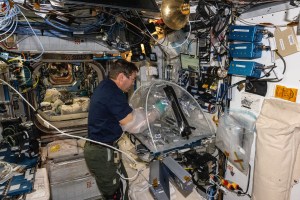 Expedition 70 Flight Engineer and NASA astronaut Mike Barratt works aboard the International Space Station's Harmony module processing protein crystal samples inside a portable glovebag to learn how to generate personalized medicines in space for astronauts.