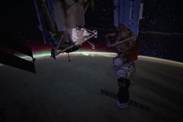 An aurora blankets Earth's horizon in this photograph from the International Space Station as it orbited 260 miles above North America. In the foreground, are the Rassvet module and the Nauka science module. The Prichal docking module and the Soyuz MS-25 crew ship are both attached to Nauka.