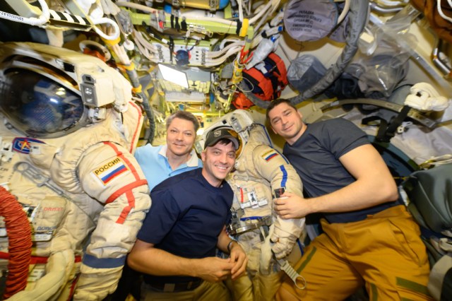 NASA astronaut Matthew Dominick (center) poses for a portrait with Expedition 71 Commander Oleg Kononenko (left) and Flight Engineer Nikolai Chub (right), both Roscosmos cosmonauts. Dominick was inside the Poisk module assisting Kononenko and Chub as they prepared their Orlan spacesuits for a spacewalk to configure hardware and install experiments on the International Space Station.