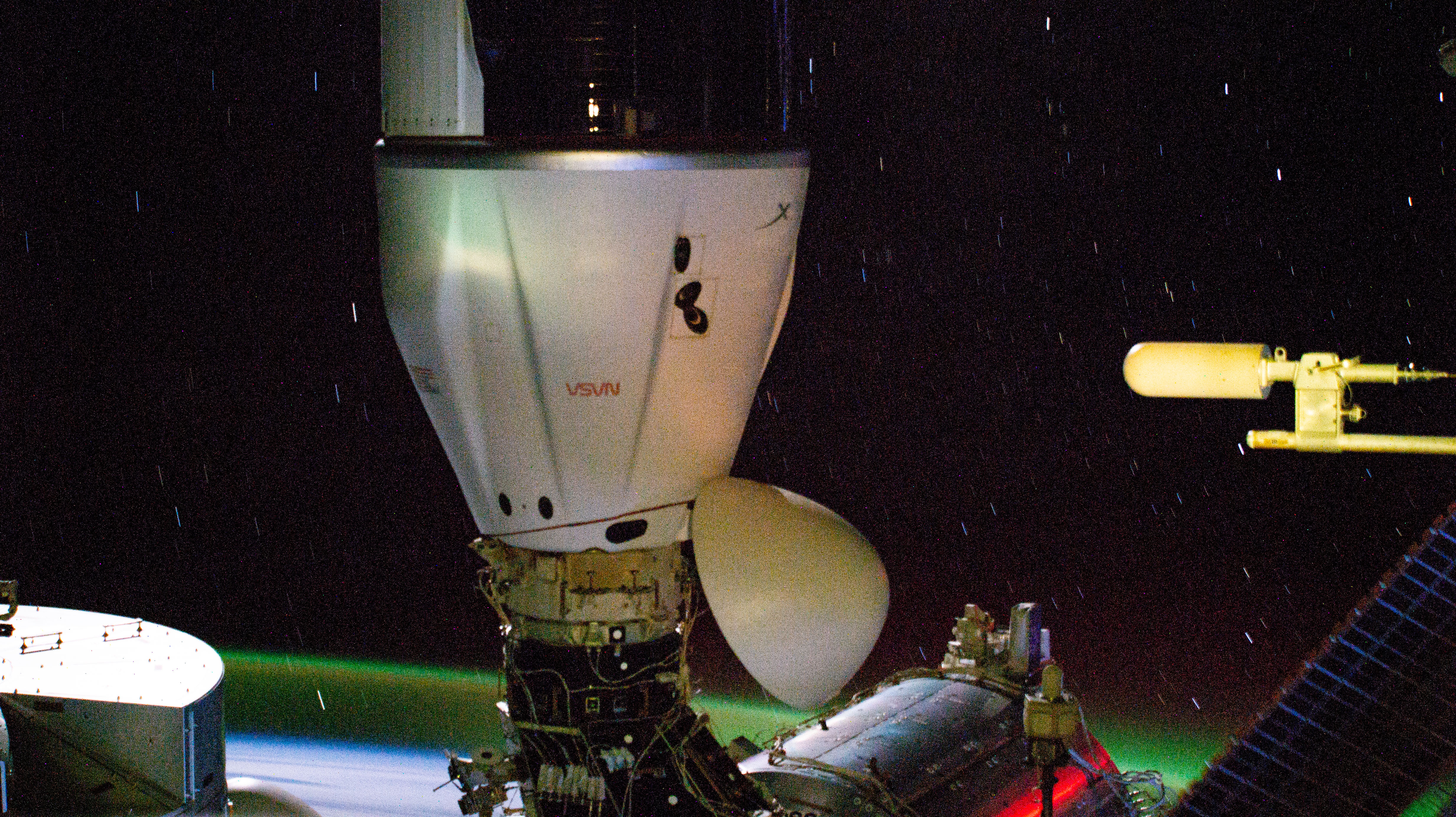 The SpaceX Dragon cargo spacecraft is pictured docked to the Harmony module's space-facing port on the International Space Station. In the background, slight star trails and an atmospheric glow above Earth's horizon are pictured in this long-duration photograph as the orbital outpost soared 267 miles above the Indian Ocean south of Africa.