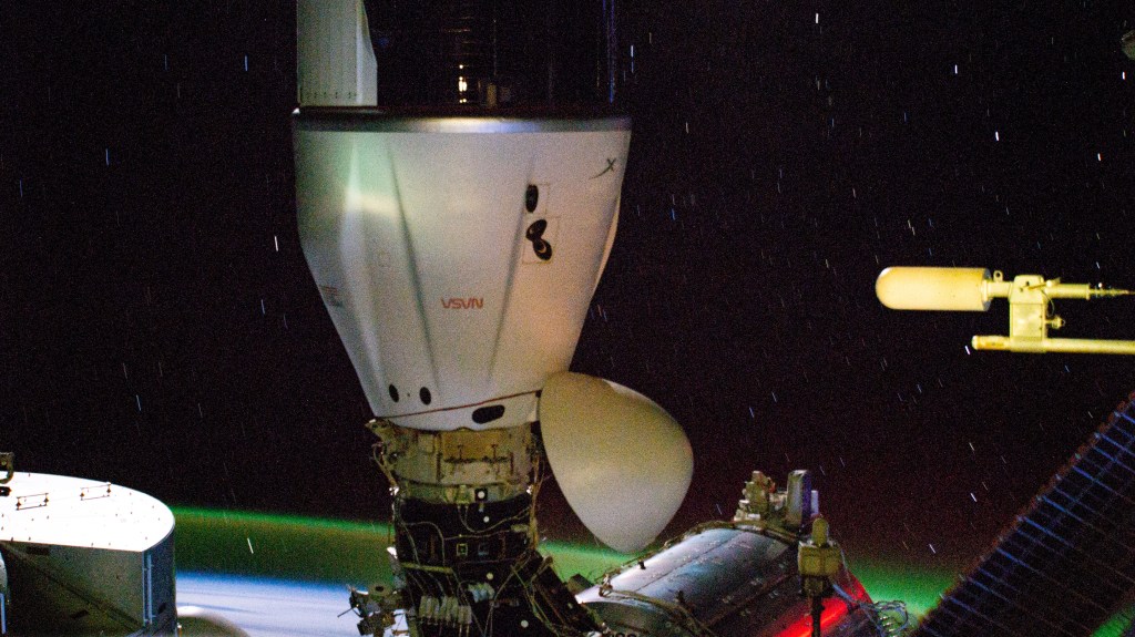The SpaceX Dragon cargo spacecraft is pictured docked to the Harmony module's space-facing port on the International Space Station. In the background, slight star trails and an atmospheric glow above Earth's horizon are pictured in this long-duration photograph as the orbital outpost soared 267 miles above the Indian Ocean south of Africa.