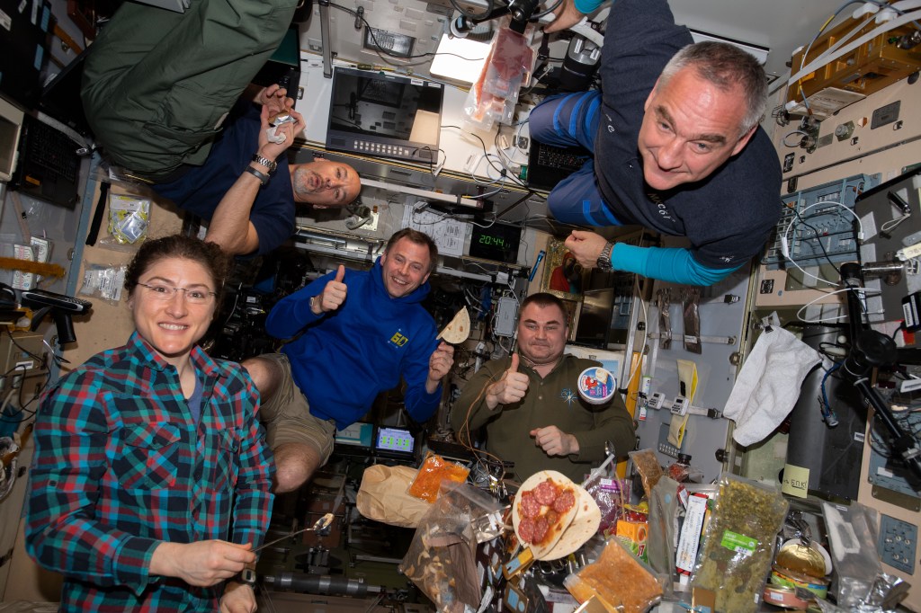 iss060e021619 (Aug. 2, 2019) --- It's dinner time aboard the International Space Station as five Expedition 60 crewmembers gather inside the Zvezda service module's galley. From left are astronauts Christina Koch, Luca Parmitano and Nick Hague with cosmonauts Alexey Ovchinin and Alexander Skvortsov.