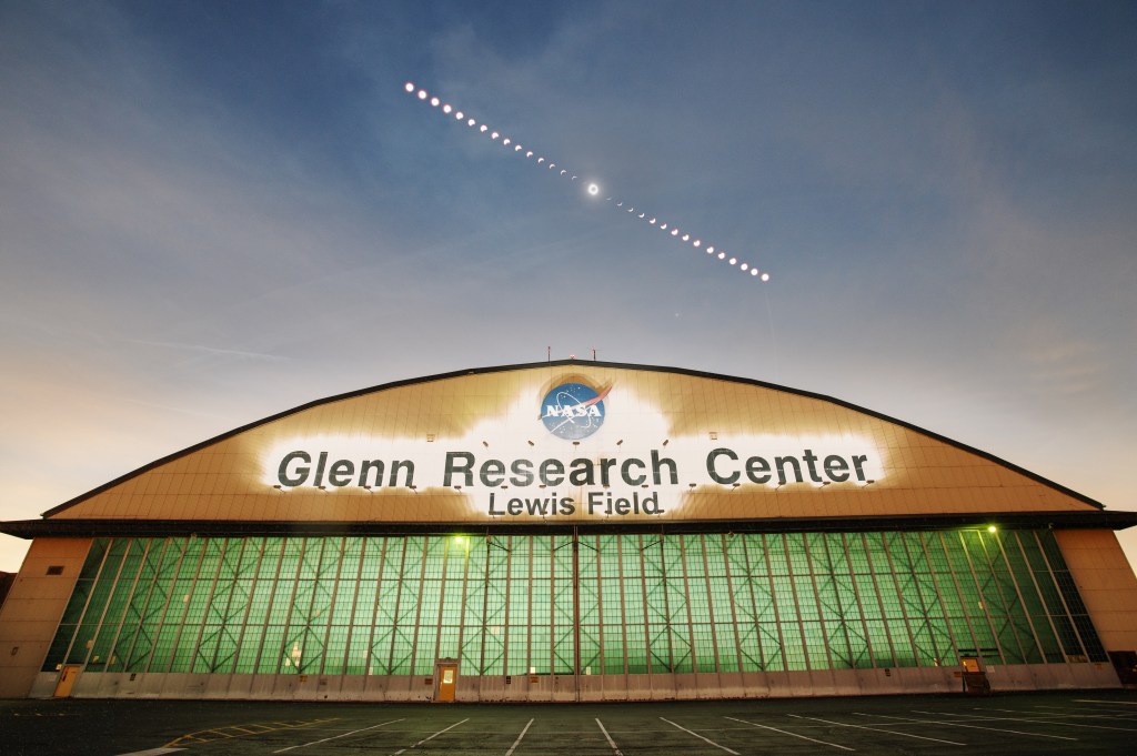 : A composite image of the phases of the April 8, 2024, total solar eclipse over the aircraft hangar at NASA’s Glenn Research Center in Cleveland.