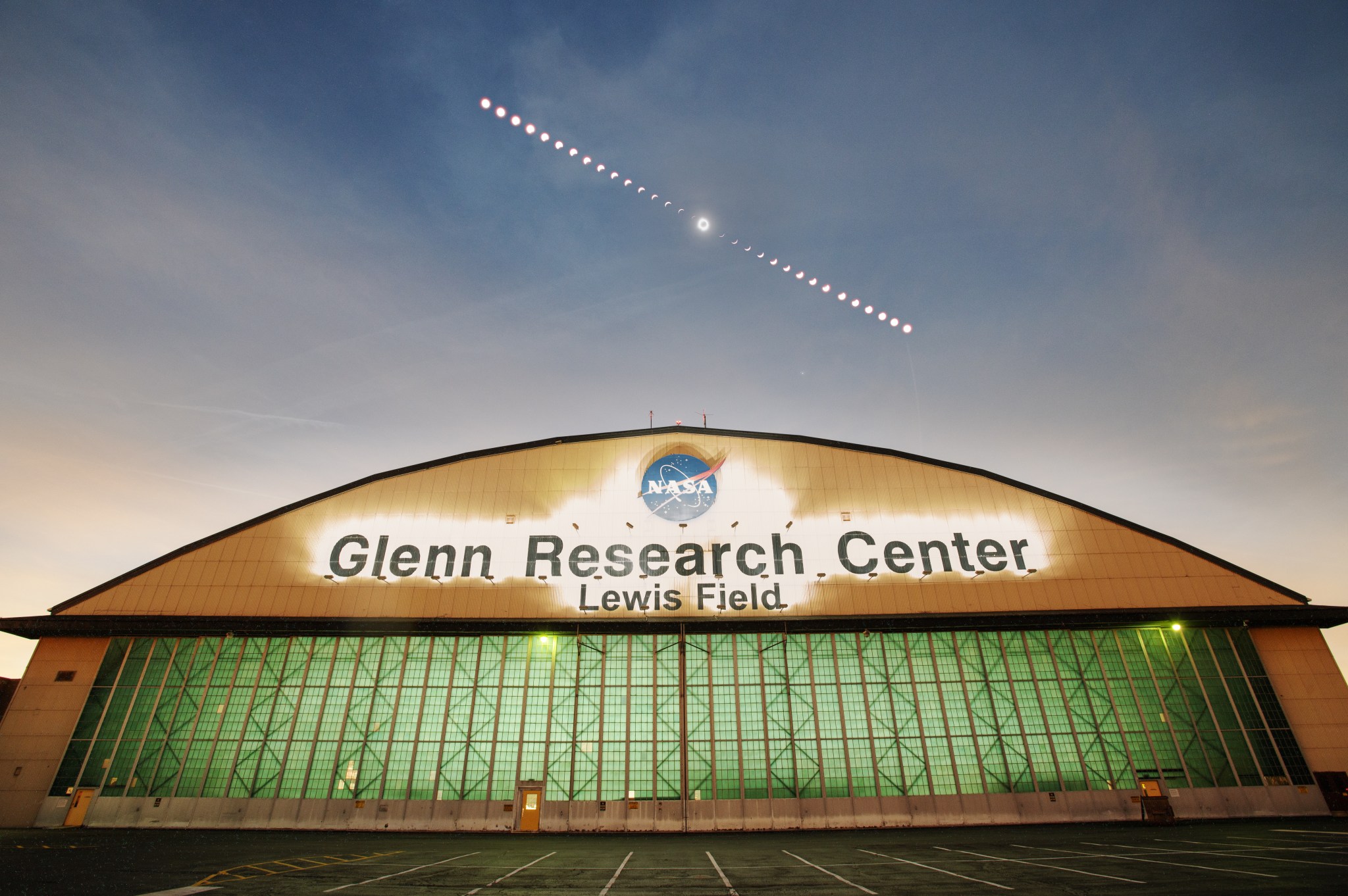 : A composite image of the phases of the April 8, 2024, total solar eclipse over the aircraft hangar at NASA's Glenn Research Center in Cleveland.