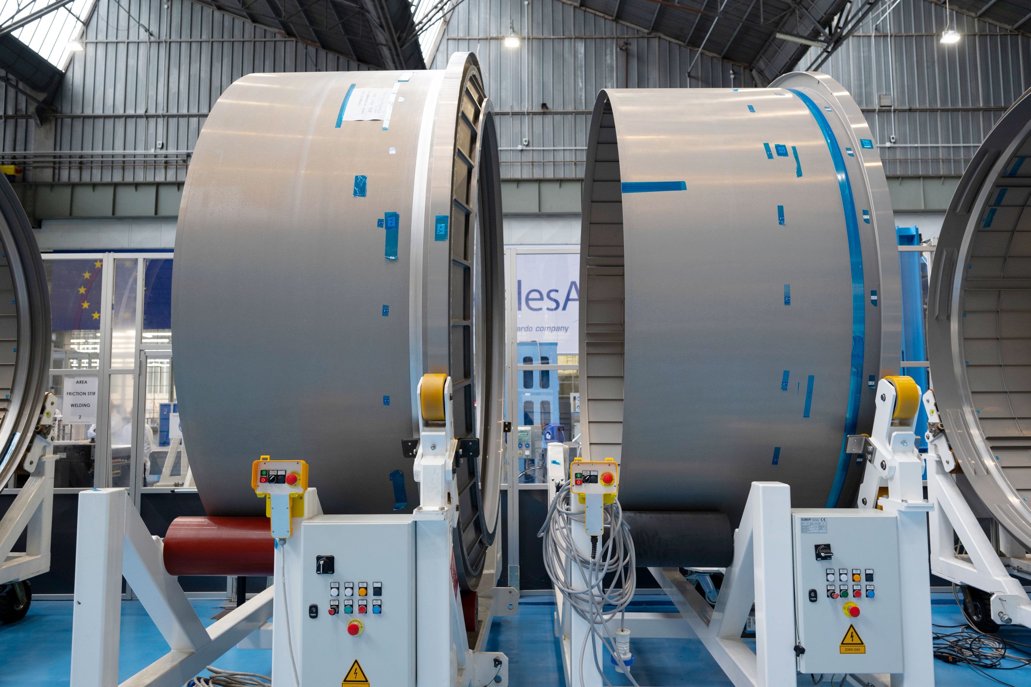 Industrial facility with two large cylindrical metallic structures supported by frameworks, equipped with electronic control units.