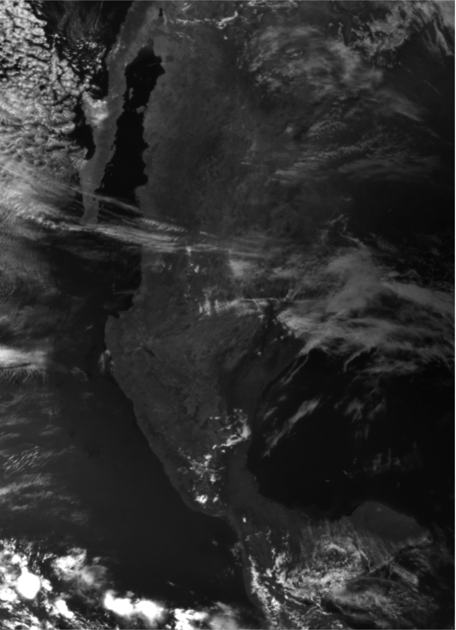 Black and White image with thin wispy clouds focused on Mexico. The land is a dim color due to the shadow of the Moon eclipsing the Sun.