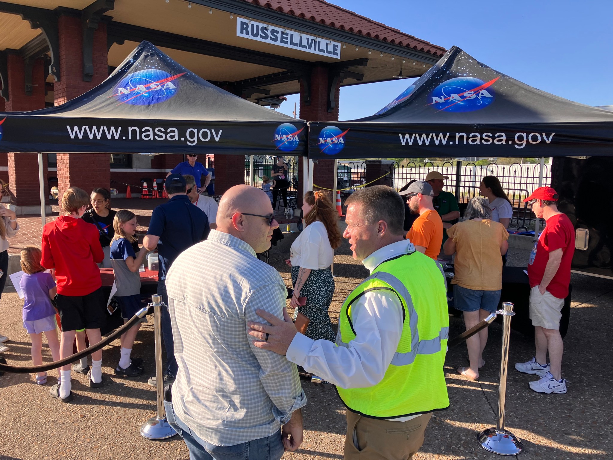 Marshall Center Director Joseph Pelfrey, left, greets Russellville, Arkansas, Mayor Fred Teague in front of NASA tents set up for visitors for the April 8 eclipse event.
