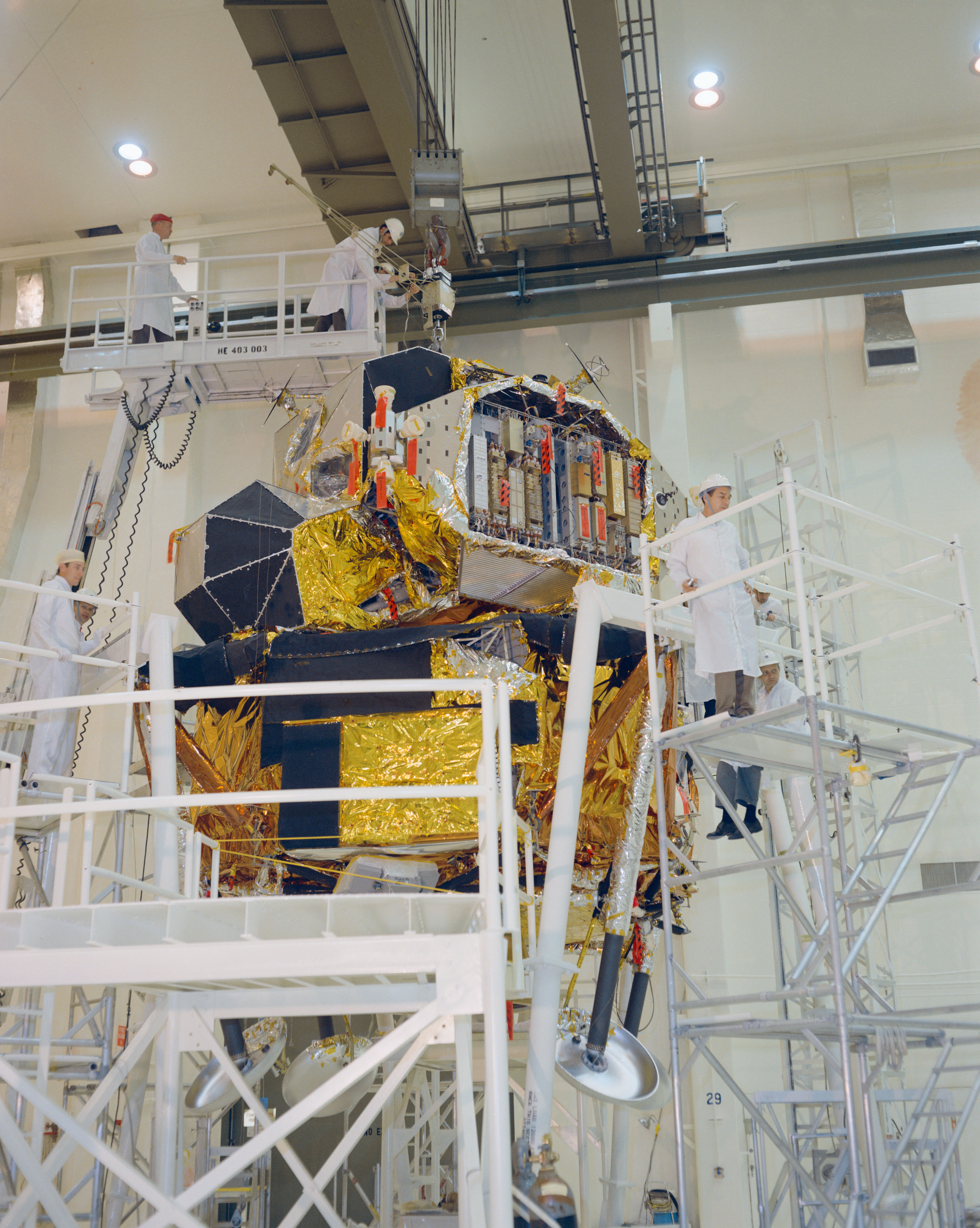 In the Manned Spacecraft Operations Building (MSOB) at NASA’s Kennedy Space Center (KSC) in Florida, workers complete attaching the landing legs to the Apollo 11 Lunar Module (LM)