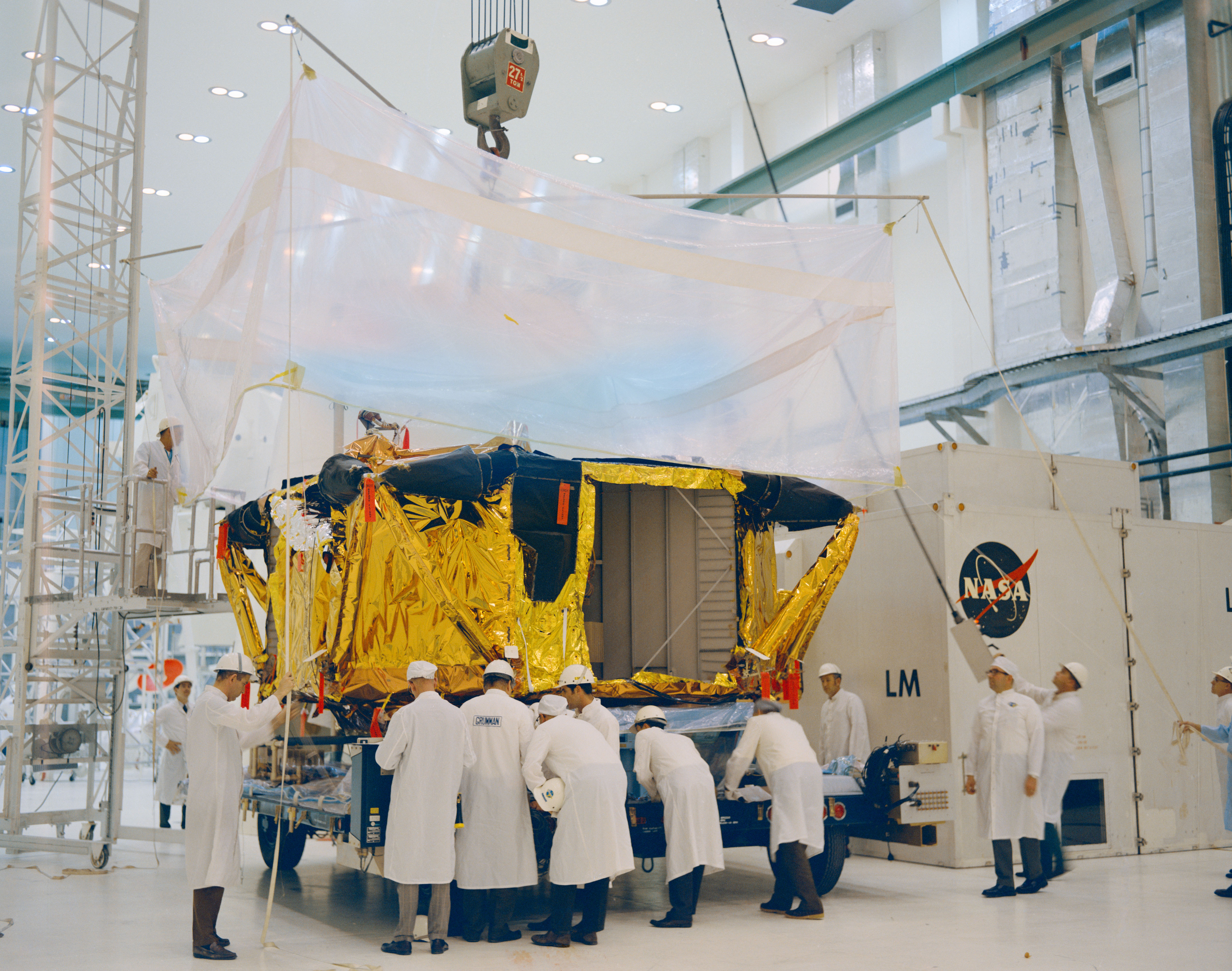 At NASA’s Kennedy Space Center (KSC) in Florida, workers unwrap the Apollo 12 Lunar Module (LM) descent stage shortly after its arrival in the Manned Spacecraft Operations Building
