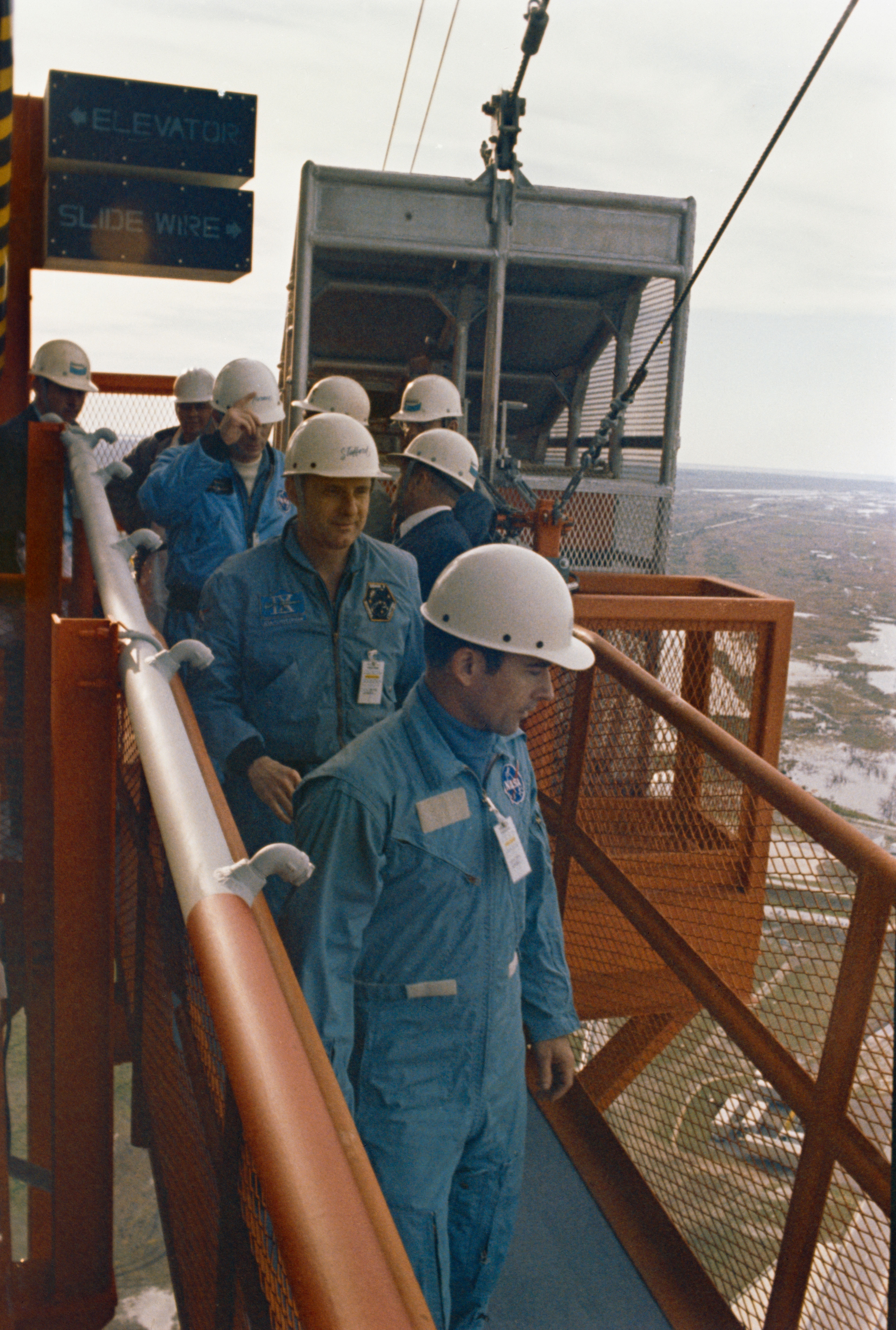 Young, front, Stafford, and Cernan inspect the slide wire escape mechanism at the top of Launch Pad 39B