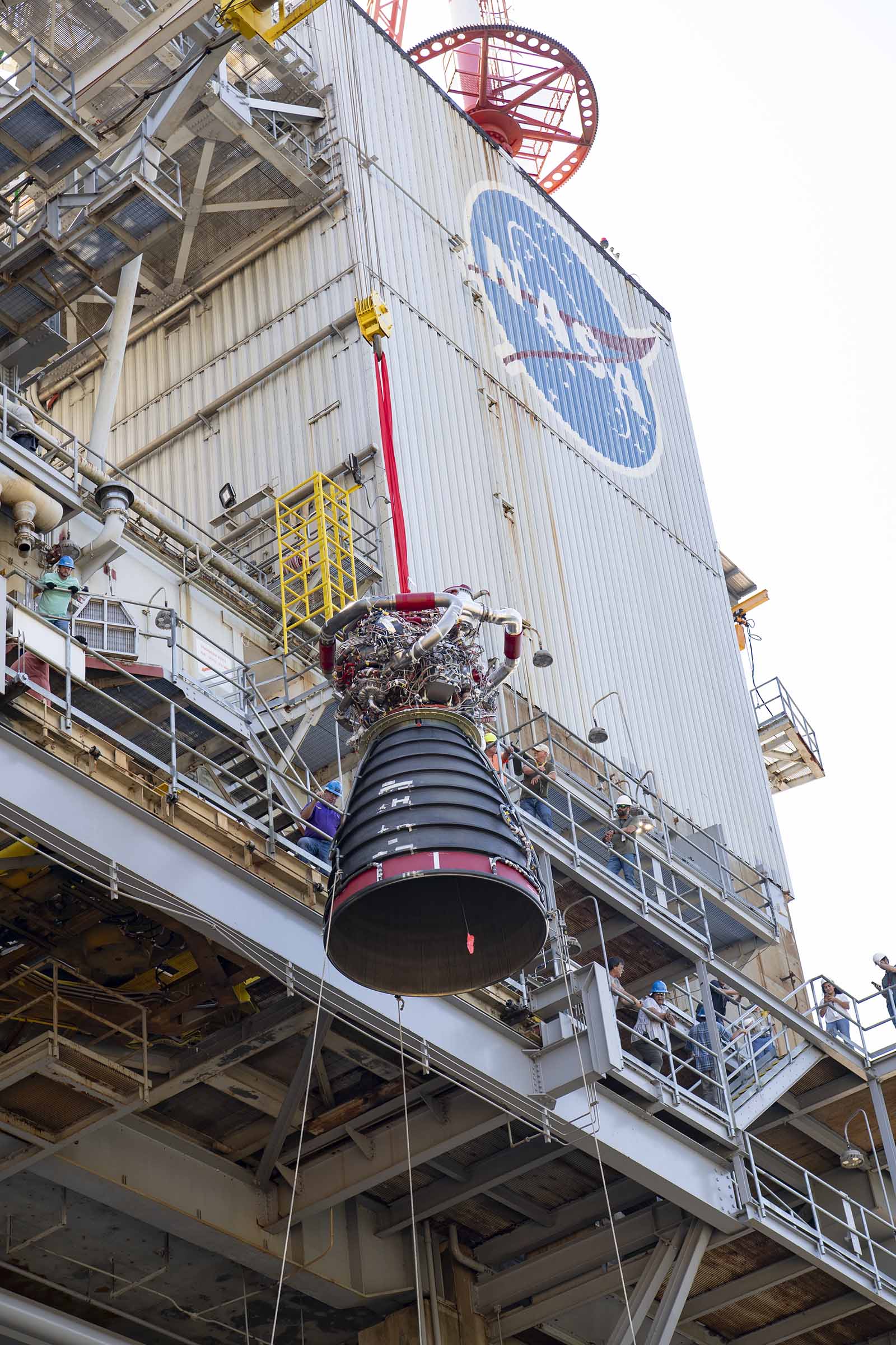 A crane lifts developmental engine E0525 onto the Fred Haise Test Stand