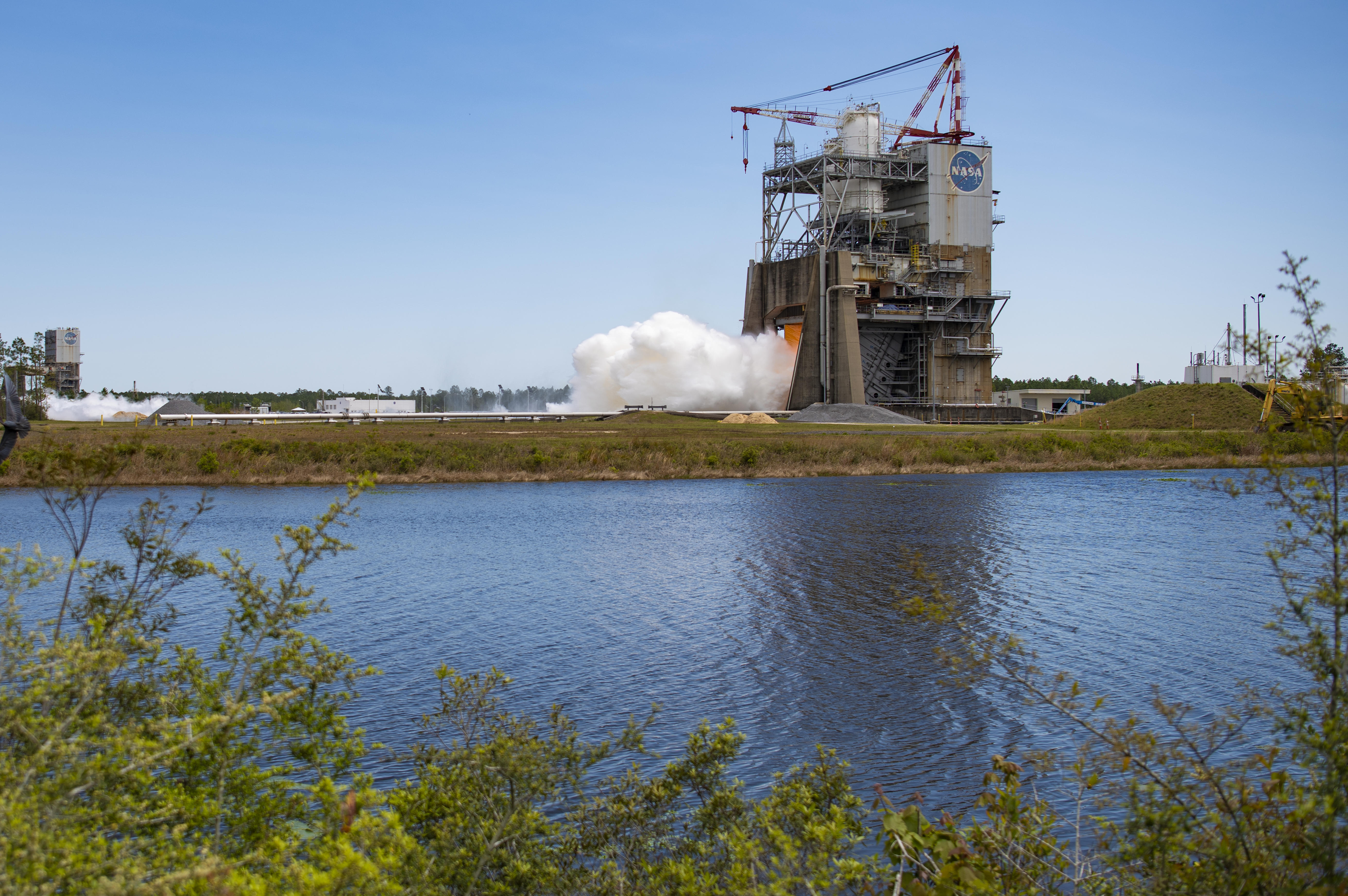a hot fire begins on the RS-25 engine as seen across the canal