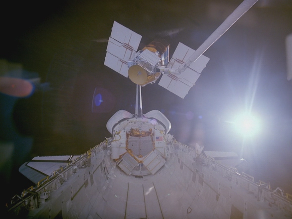 Using the RMS, Hart moving Solar Max to the Flight Support Structure in Challenger's payload bay