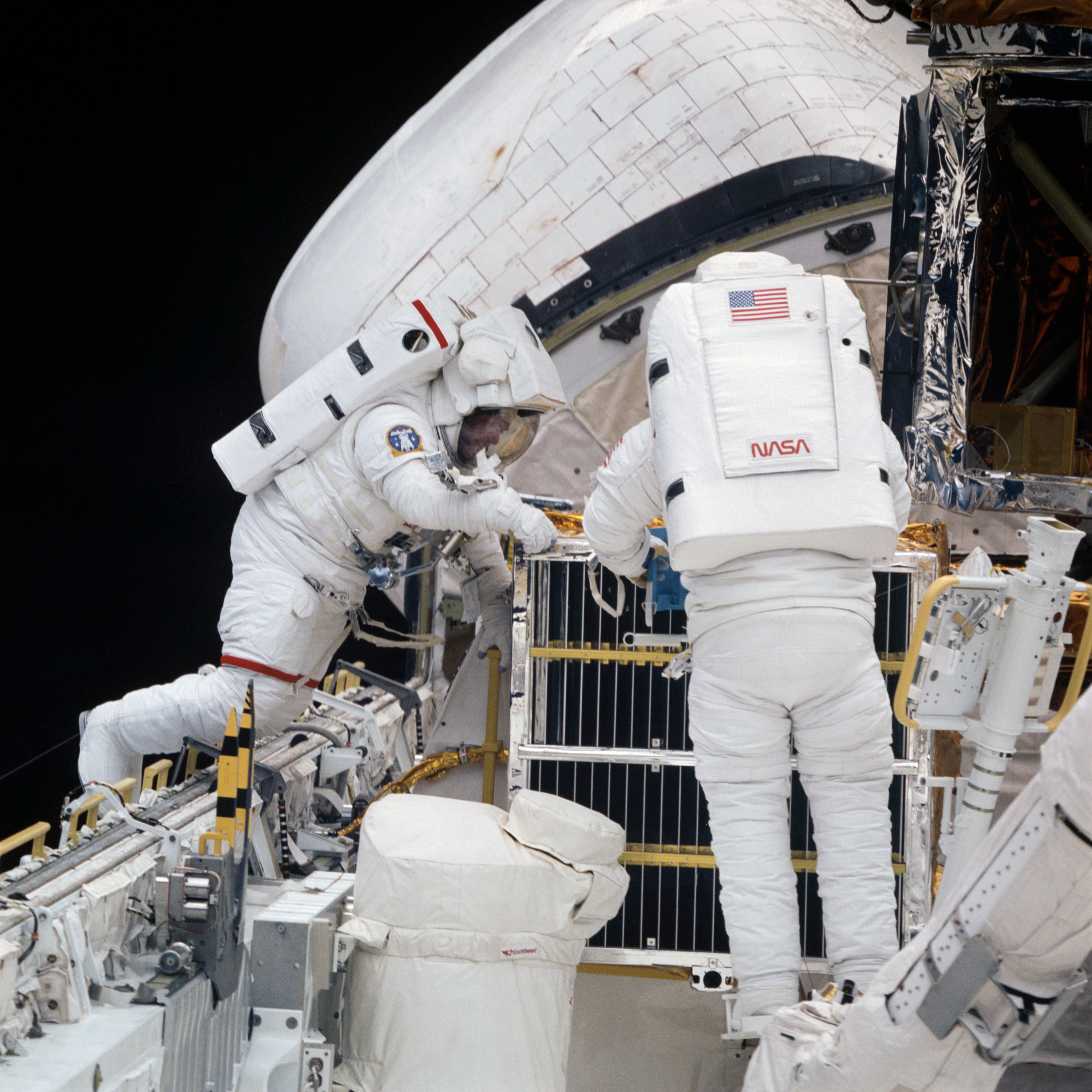 Astronauts George D. “Pinky” Nelson, left, and James D. “Ox” Van Hoften replace Solar Max’s attitude control system module during the second STS-41C spacewalk