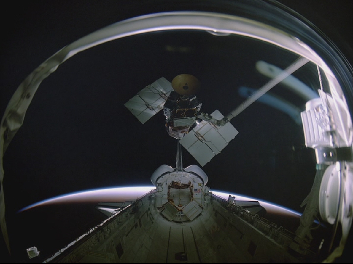 Terry J. Hart lifts the repaired Solar Max out of Challenger's payload bay