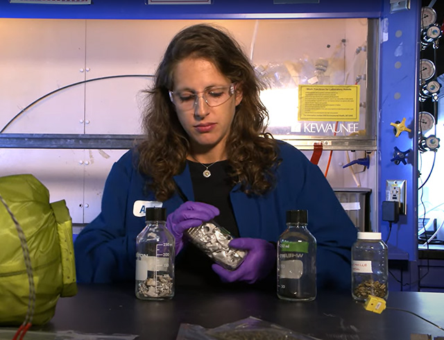 NASA space waste engineer Annie Meier inspects different waste samples in bottles