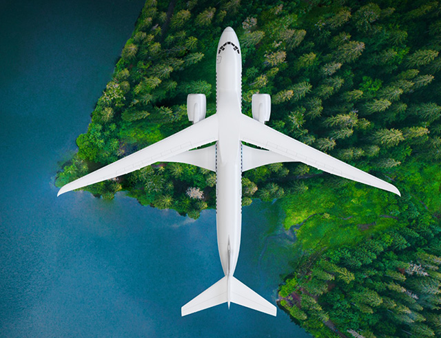 A transonic-truss braced wing aircraft in flight over water and treetops