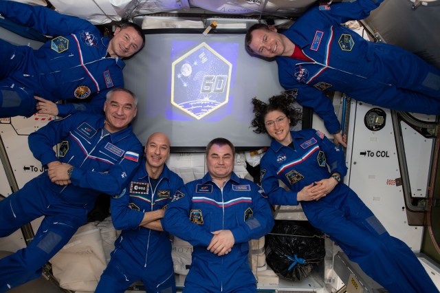 iss060e062085 (Sept. 15, 2019) --- The six-member Expedition 60 crew from the United States, Russia and Italy gathers for a portrait inside the International Space Station's Unity module. In the front row from left are, NASA astronauts Andrew Morgan and Nick Hague and Roscosmos cosmonaut Alexander Skvortsov. In the back are, ESA (European Space Agency) astronaut Luca Parmitano, Roscosmos cosmonaut and station commander Alexey Ovchinin and NASA astronaut Christina Koch. On the wall to the right, are stickers representing the insignia of the space shuttle missions that visited the orbiting lab.