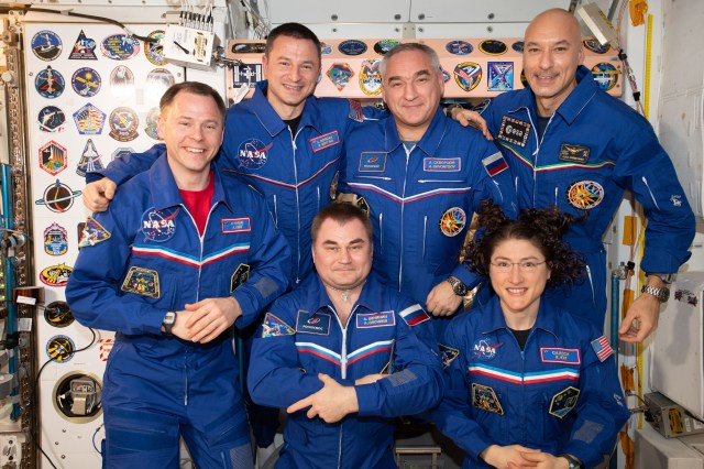 iss060e062023 (Sept. 15, 2019) --- The six-member Expedition 60 crew from the United States, Russia and Italy gathers for a portrait inside the International Space Station's Unity module. Clockwise from left, are NASA astronauts Nick Hague and Andrew Morgan, Roscosmos cosmonaut Alexander Skvortsov, ESA (European Space Agency) astronaut Luca Parmitano, NASA astronaut Christina Koch and station commander Alexey Ovchinin of Roscosmos. On the wall to the rear of the crew, are stickers representing the insignia of space station crews and space shuttle missions that visited the orbiting lab.