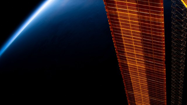 iss060e008812 (July 15, 2019) --- A portion of the International Space Station's main solar arrays drape the foreground as the orbiting lab flew 257 miles above Mongolia and across China. The Sun's rays light up Earth's thin atmosphere during a period between night and day.