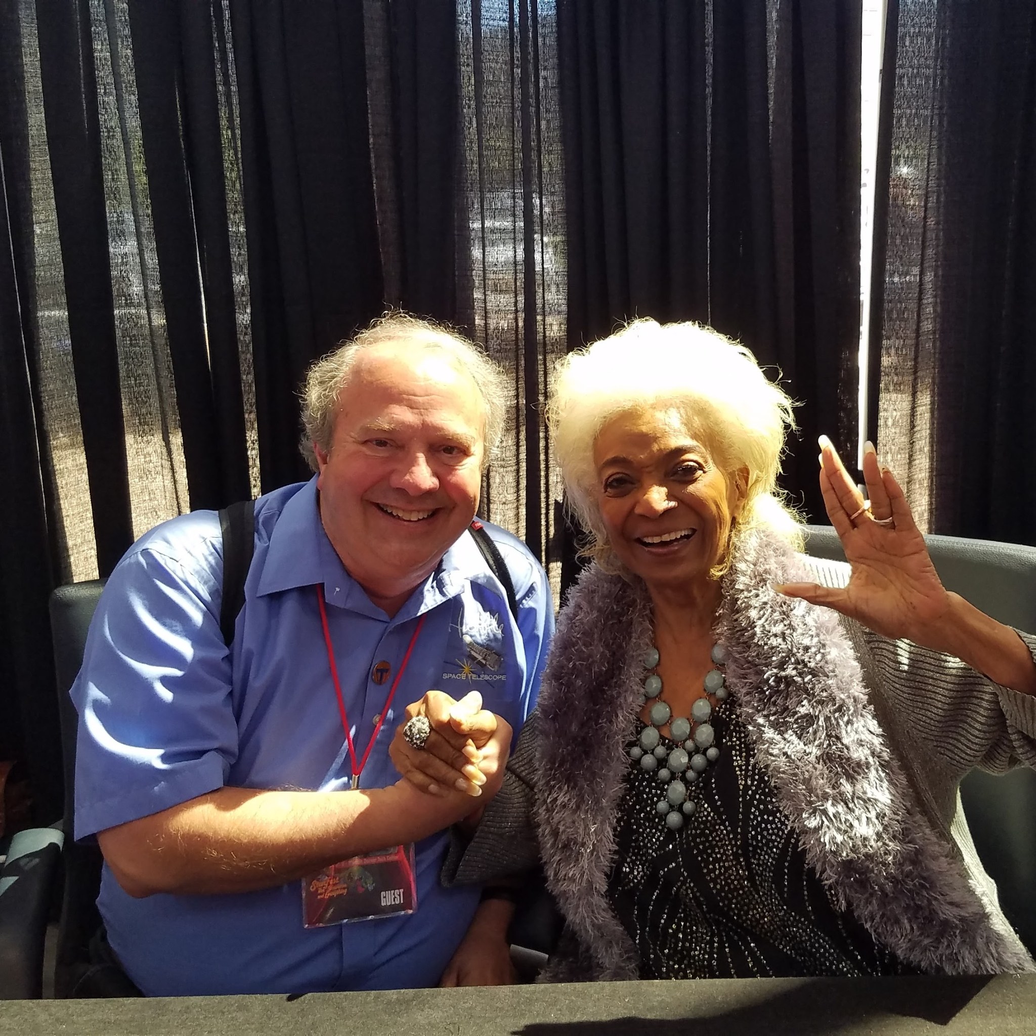 Ken Carpenter and Nichelle Nichols smile for a photo. Nichelle is holding her left hand in the Vulcan salute hand gesture.