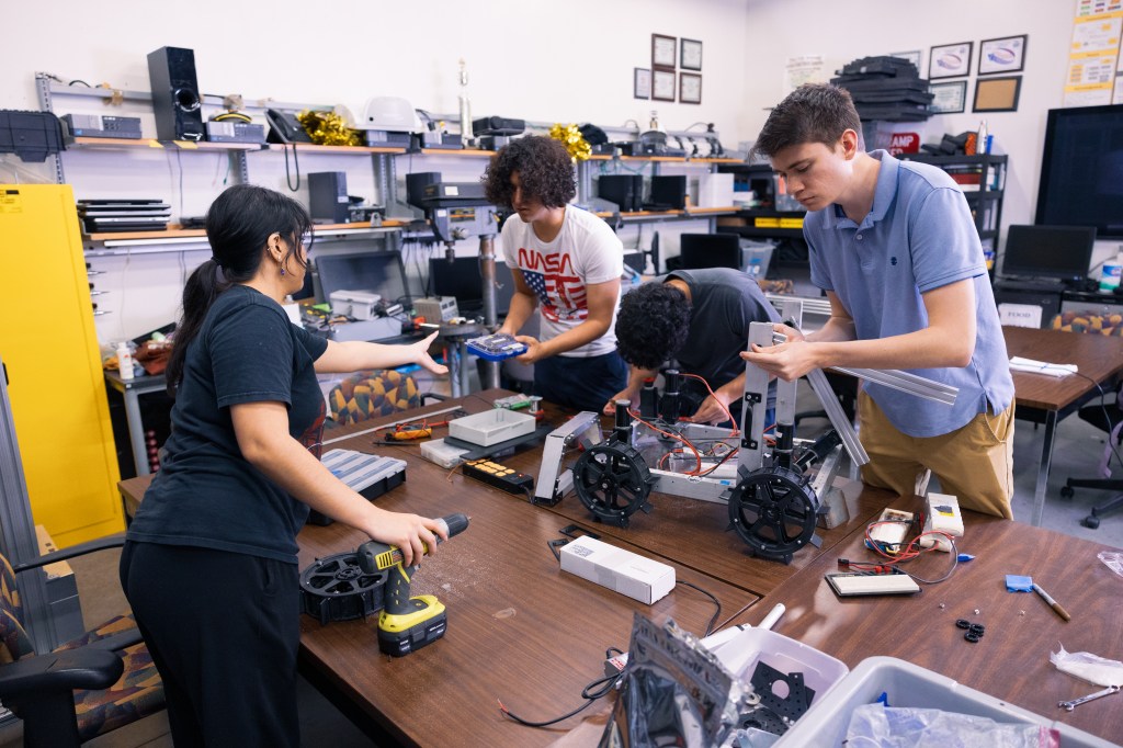 From left to right, Cielo Torres, Jacob Liorca, and Gavin Fitzgerald work on a robotic rover inside the University of Central Florida's robotics lab ahead of the 2024 Lunabotics Challenge.