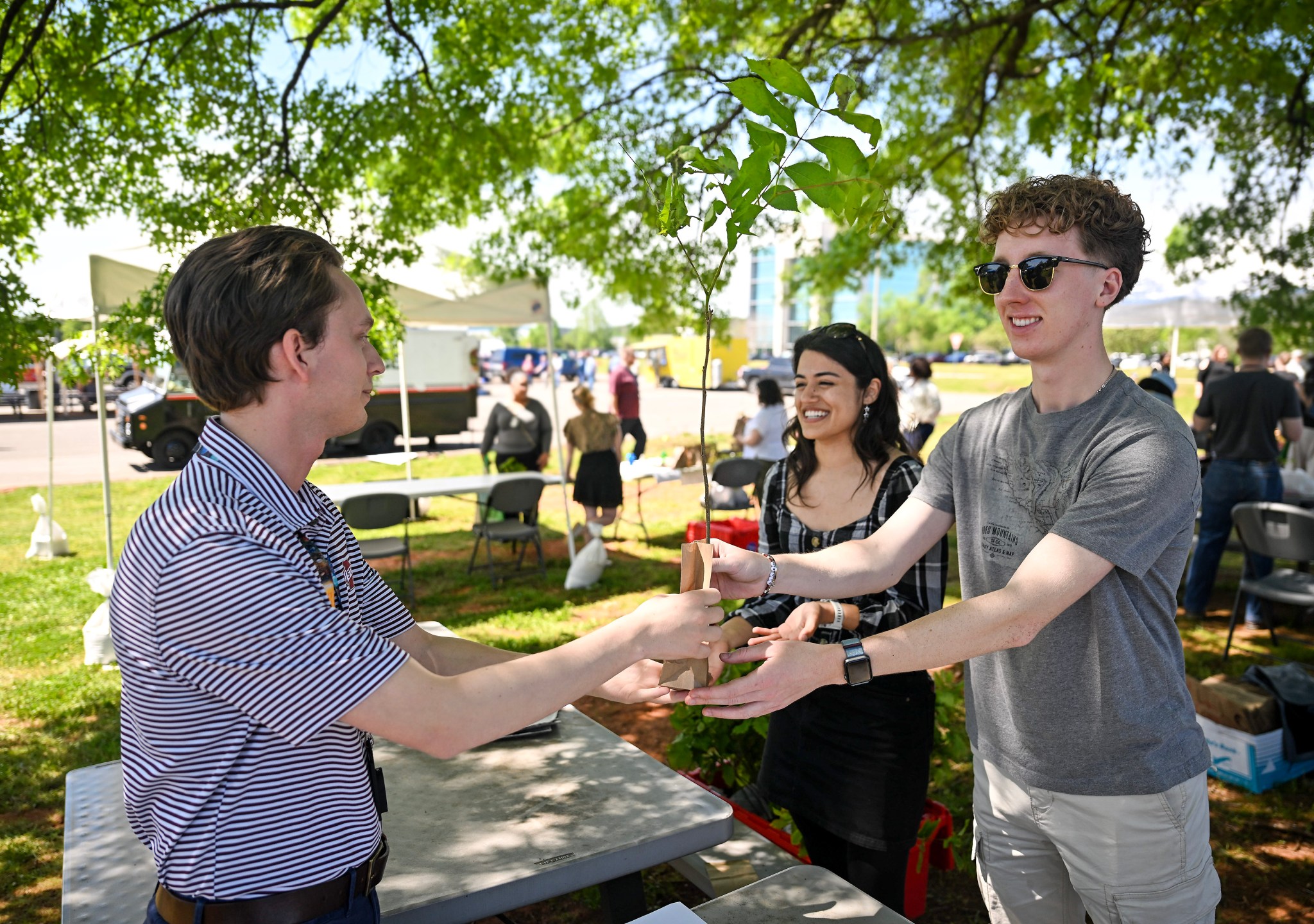 Earth Day volunteers Sahana Parker, center, and Jacob Jolley, right, help hand out hundreds of saplings April 25 in a tree giveaway organized by Marshall’s Environmental Engineering and Occupational Health Office and Green Team.