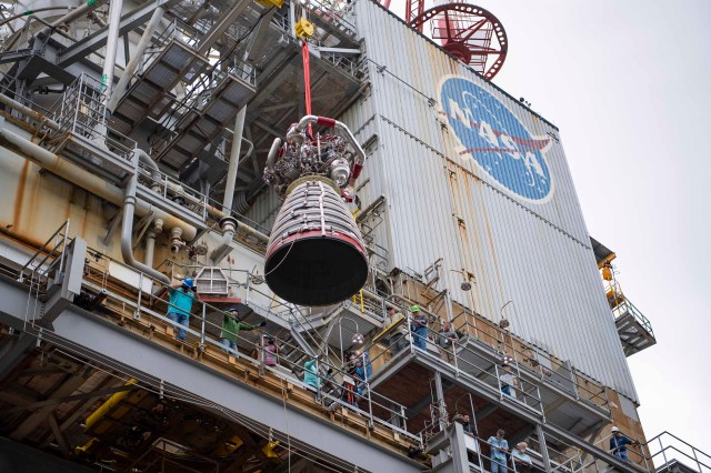 a RS-25 engine is suspended in air as it is being removed from the Fred Haise Test Stand