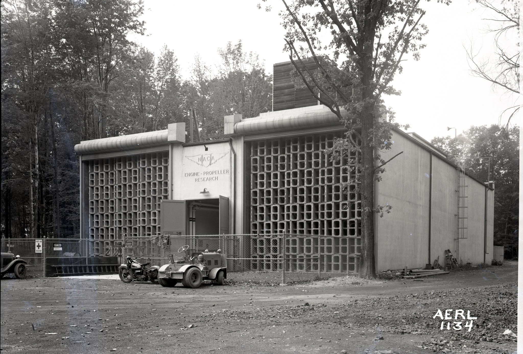 A black-and-white-image of a concrete building with a sign above the door that says, “NACA Engine Propeller Research.”