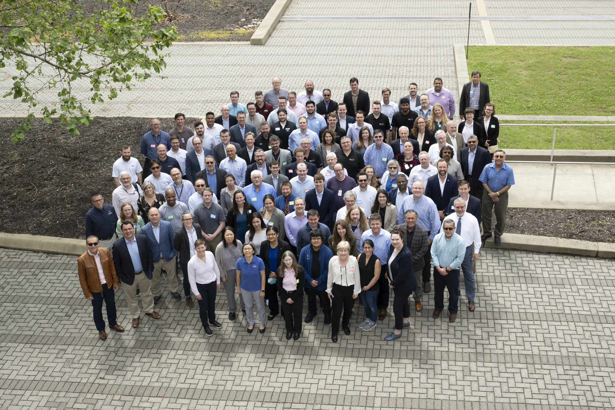 A large group of composite researchers assembled in a courtyard looking up at the photographer.