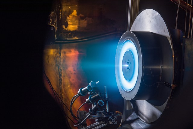 blue glow emanates from a ring-like Hall-effect Thruster