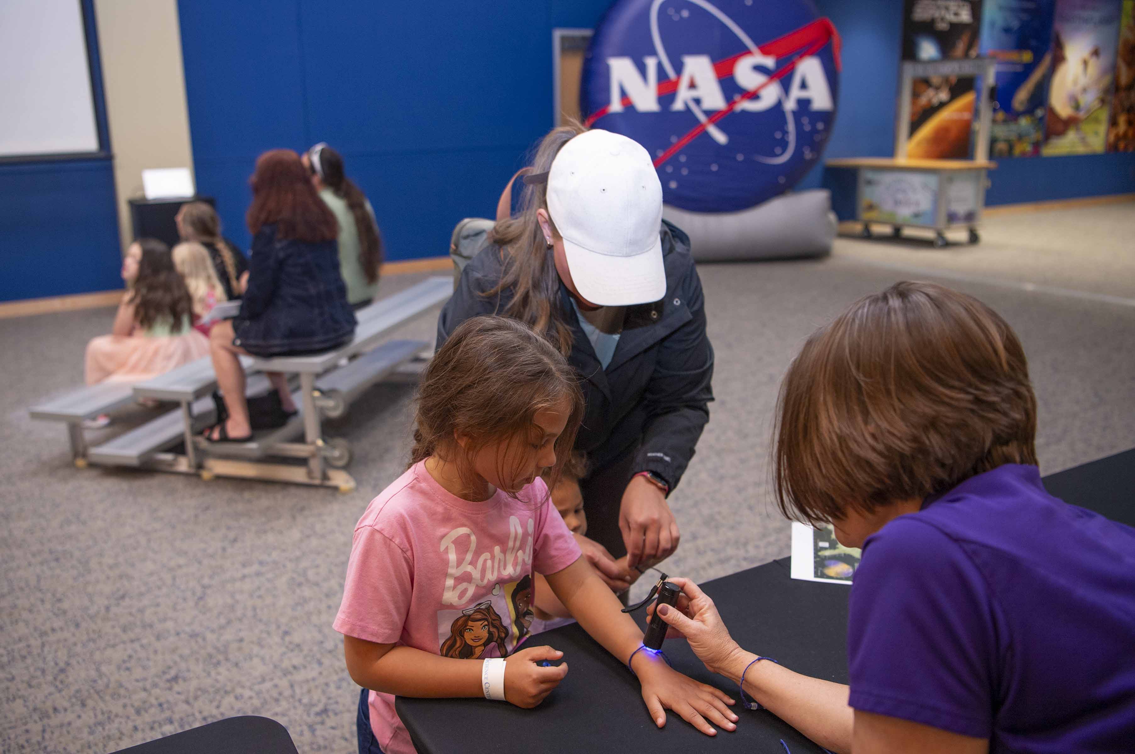 a young visitor at INFINITY Science Center interacts with NASA Visitor Relations Specialist Holley Argus