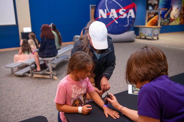 a young visitor at INFINITY Science Center interacts with NASA Visitor Relations Specialist Holley Argus