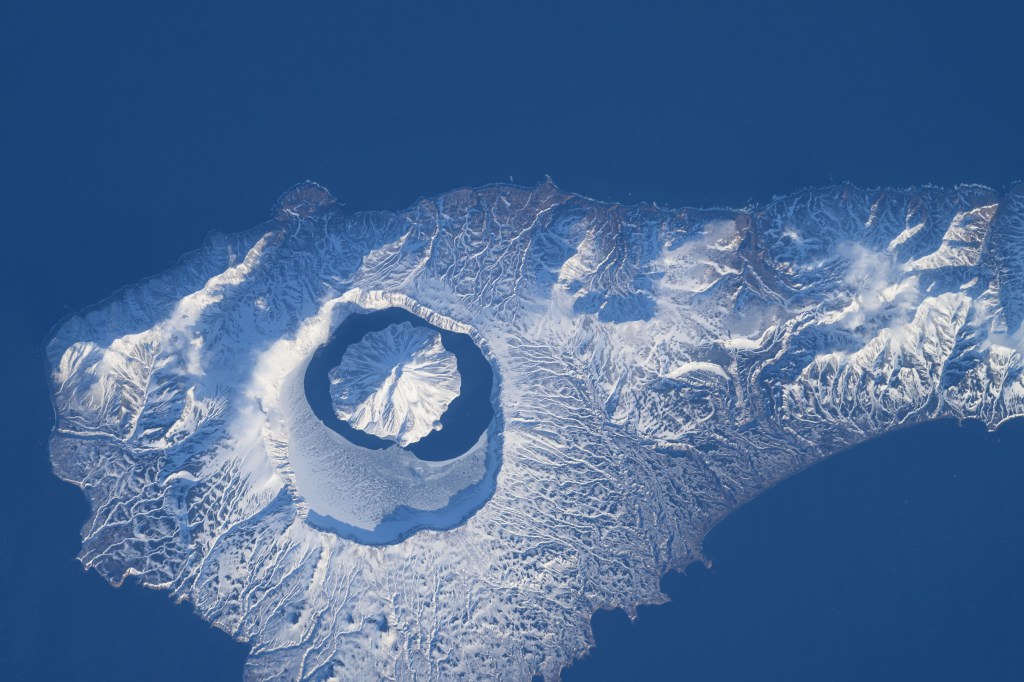iss071e046421 (April 29, 2024) -- In the north end of the Kuril island chain is Onekotan, an uninhabited volcanic island, home to Krenitsyn volcano, pictured here from the International Space Station as it orbited 260 miles above. The volcano rises 900 meters (~3,000 feet) at its highest point and surrounding it is Tao-Rusyr Caldera.