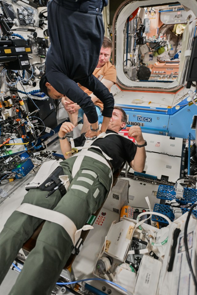 Flight Engineer Jeanette Epps practices cardiopulmonary resuscitation (CPR), or chest compressions, on Flight Engineer Mike Barratt, both NASA astronauts, as Roscosmos cosmonaut Alexander Grebenkin monitors. The trio reviewed medical procedures, hardware configurations, and commnication protocols in the unlikely event of an emergency aboard the International Space Station.