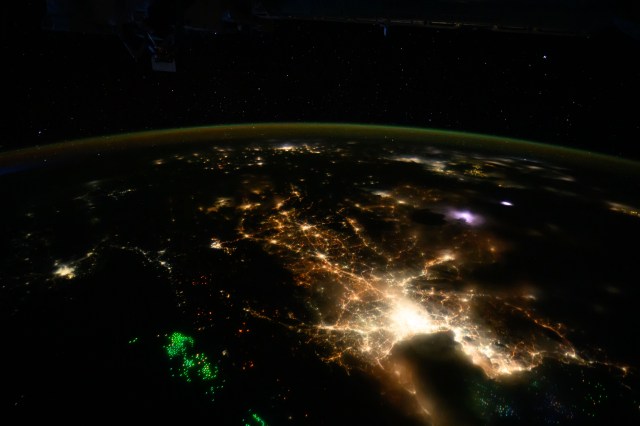 The city lights of Bangkok, Thailand, and its suburbs contrast with the green lights of the fishing boats on the Gulf of Thailand and the Andaman Sea.