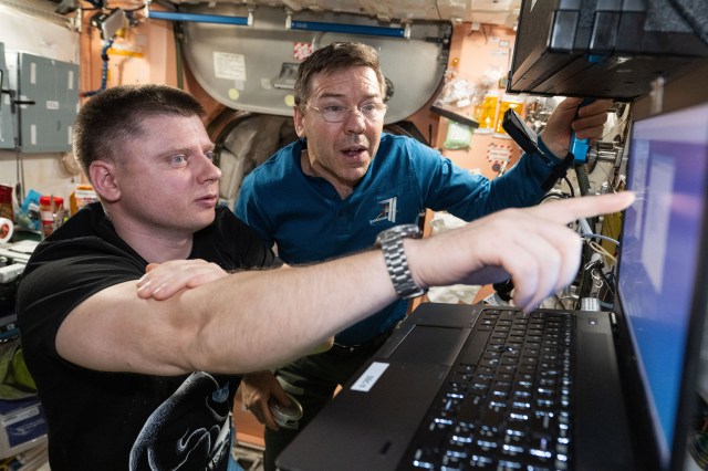 Expedition 71 crew members (from left) Alexander Grebenkin from Roscosmos and Mike Barratt from NASA view laptop computer operations aboard the International Space Station's Unity module.