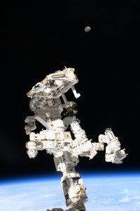 The International Space Station's Dextre, the fine-tuned robotic hand, attached to the Canadarm2 robotic arm dominates the frame with the waxing gibbous Moon (at top) in the background and the Indian Ocean 259 miles below.