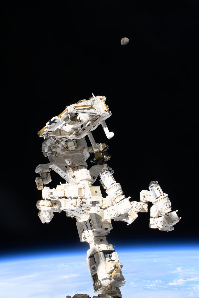The International Space Station's Dextre, the fine-tuned robotic hand, attached to the Canadarm2 robotic arm dominates the frame with the waxing gibbous Moon (at top) in the background and the Indian Ocean 259 miles below.