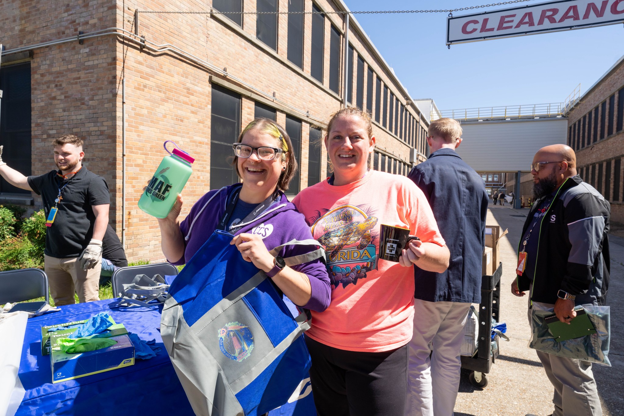 Crystal Farmer, left, and Jennifer York of Boeing show off “MAF Goes Green” giveaways handed out during the April 22 cleanup activities.