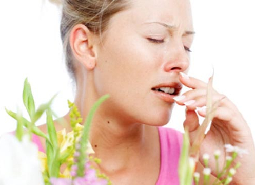 Woman about to sneeze due to flowers near her.