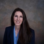 Rae Ann Meyer headshot of a women with long brown hair and black jacket and blue shirt from NASA