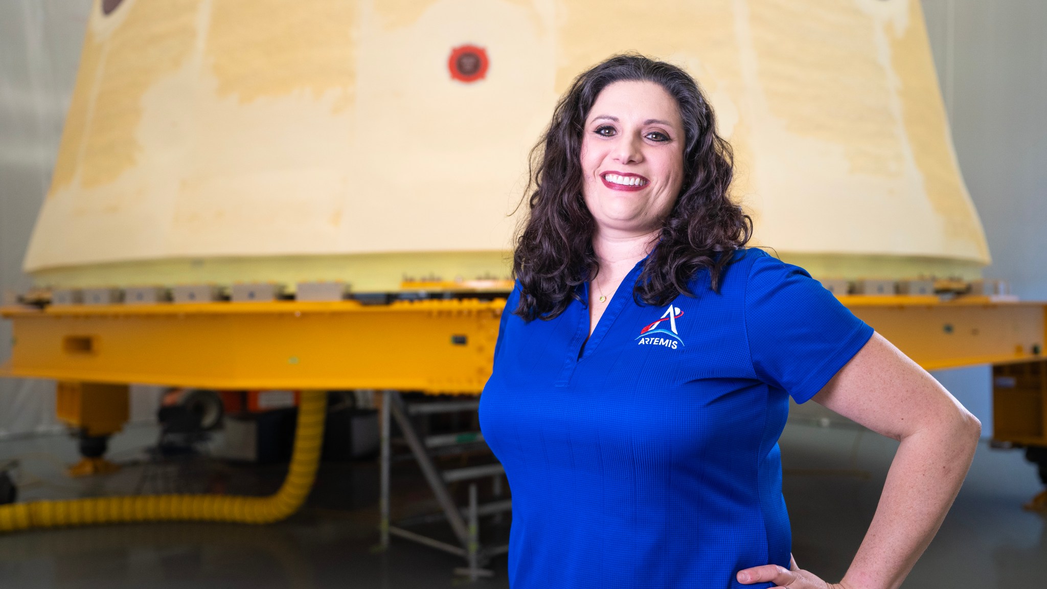Lauren Fisher stands in front of the launch vehicle stage adapter for NASA’s SLS (Space Launch System) rocket.